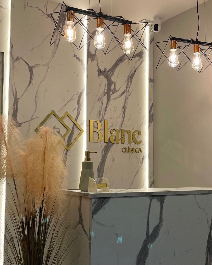 Recepção da Blanc com o logo na parede de mármore